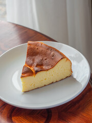 Burnt Basque Cheesecake. A slice of cheese cake with burnt cake surface on white plate.