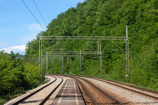 Railway tracks, rails and platforms in a train station in a middle of a forest in Serbia, electrified, with power overhead line, on a double track main railroad line...
