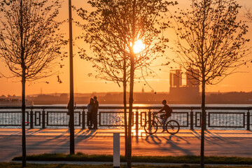 Fototapeta na wymiar Silhouettes of people walking along the embankment