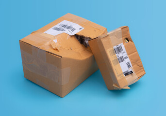 Damaged cardboard box with hole on blue background,cardboard box destroyed in shipping - obrazy, fototapety, plakaty