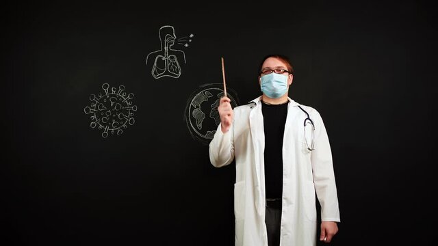 Scientist doctor in lab coat explains about coronavirus at blackboard. Sketches of spread of virus on planet. E-learning during pandemic. Instructions why it is important to wear protection on face.