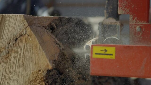 Push towards a large saw cutting a slice through a tree trunk at a sawmill.