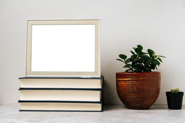 A picture frame placed on a book with a small plant pot