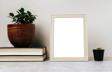 A picture frame placed on a book with a small plant pot