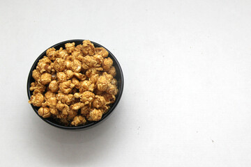 Freshly made caramel popcorn in a container accompanied by drinks and watching movies or television
