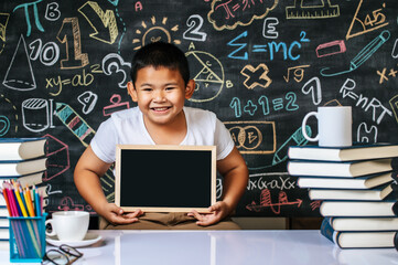 Child sitting and holding blackboard in the classroom