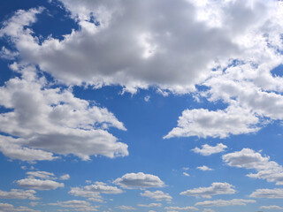 Beautiful background photo looking up at blue sky and fluffy white clouds on a sunny day. Copy space.