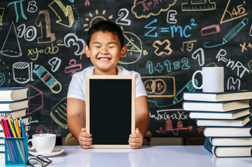 Child sitting and holding blackboard in the classroom
