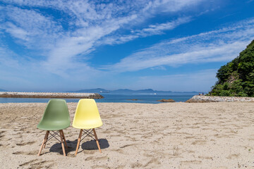 青空の下、砂浜に二人用の椅子