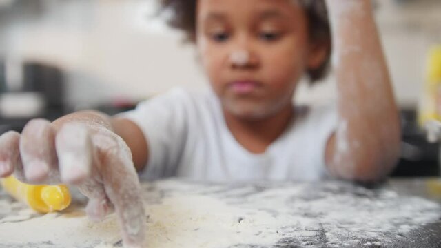 Family baking - black little girl playing with a flour on the table