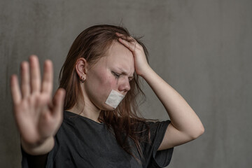 Crying teenage girl with covered her mouth showing a stop sign with her hand