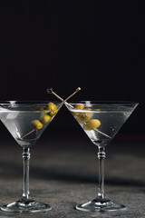martini glass with olives against black 
