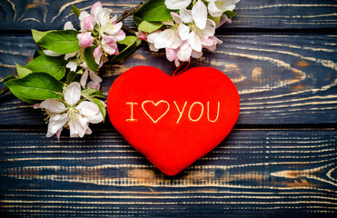 A symbol of love and a blooming Apple branch on a brown wooden background.