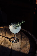 gimlet lime vodka gin cocktail with rosemary sprig on wood barrel 