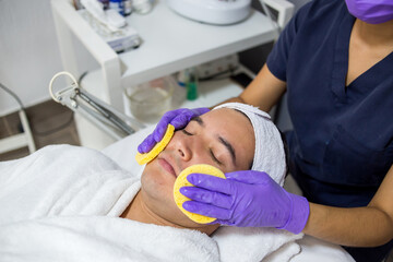 Cosmética masculina. Esteticista Hombre guapo recibiendo tratamiento facial en el spa