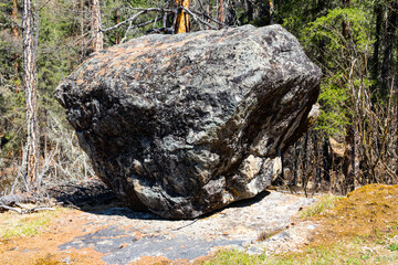 a huge boulder stands in the taiga wilderness
