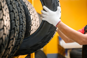 Asian male tire changer Checking the condition of off-road tires in stock so that they can be...