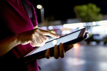 Asian woman calling taxi with digital device at night in urban.