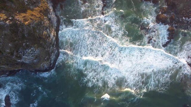 Beautiful Sunrise on the Oregon Coast - Mossy Haystack Rock and Crystal Clear Blue Water Crashing Against the Pacific Ocean Coast, Sea birds flying above 4K 30fps Aerial Drone Footage Straight Down