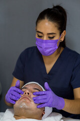 Cosmética masculina. Esteticista Hombre guapo recibiendo tratamiento facial en el spa