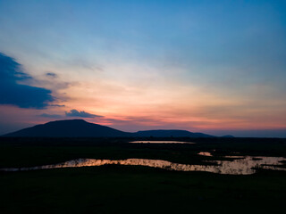 Aerial view landscape of lakeshore during dusk sky in beautiful lake with silhouette mountain.