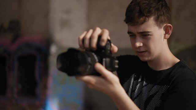 Focused male teenager taking photos with DSLR camera, slow motion