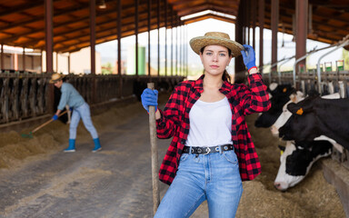 Portrait of active woman farm worker engaged in livestock breeding taking care of cows
