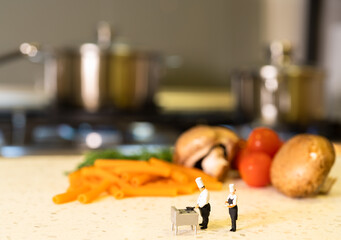 Miniature chefs with pasta, mushrooms , tomatoes and dill herb background