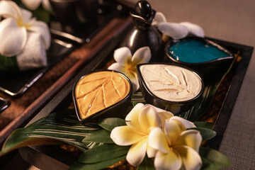 Jar with different creams and Plumeria flowers for organic care. Spa and relaxation. Close-up. Thailand