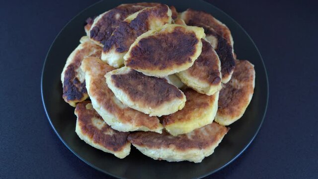 Potato cakes, ukrainian name potato zrazy, stuffed mushrooms or meat or cheese with herbs cream are fried in vegetable oil on black background, close up, rotates. Traditional Ukrainian cuisine
