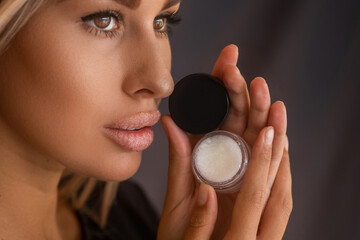 Beautiful young woman with clean perfect skin uses lips sugar scrub. Spa, skincare and wellness....