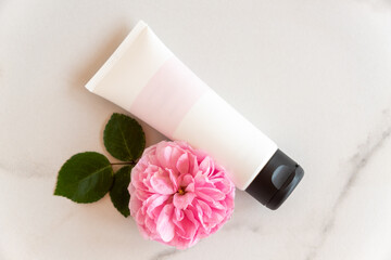 pink and white tube with rose face or body cream or scrub decorated with pink rose flowers. Skin care concept. Unbranding mockup