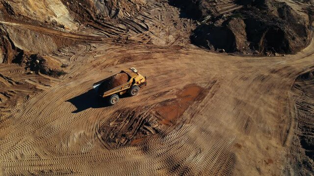 Mining truck transported sand from the open pit. Haul truck working in quarry gold mine. Arial view of the opencast mine. Limestone and gravel is excavated from ground. Mining industry.
