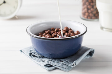 Milk is poured into a plate with round cocoa flakes. Dry breakfast.
