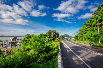 Panoramic natural background of green meadows along the reservoir, surrounding roads and winds and beautiful morning sunlight.
