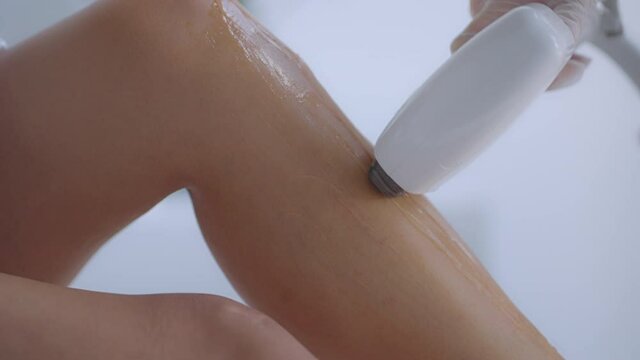Beautician doctor doing elos hair removal depilation on attractive young woman legs. woman legs getting pulses of laser light destroy hair follicle. Laser hair removal procedure beautician salon.