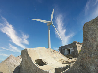 Ruins of a sea fort in the foreground. Wind turbine against the blue sky.