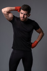 Young man in sportswear with hand wraps on grey background