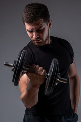 Fototapeta na wymiar Concentrated young man performing bicep curl with dumbbell