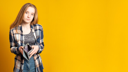 Banner copy space. Sad young girl, dressed in denim shorts and a shirt, holding empty wallet. Cute...