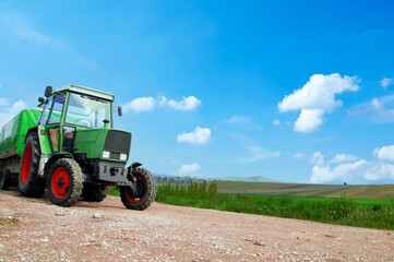 Farming, covered wagon, tractor with trailer moving on the road along vineyards on a sunny day in Rhineland Palatinate, Germany