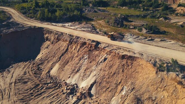 Mining truck transported sand from the open pit. Haul truck working in quarry gold mine. Arial view of the opencast mine. Limestone and gravel is excavated from ground. Mining industry.