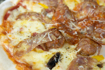 Selective focus and top view shot of original homemade thin pizza with a lot of melted cheese, sausage and pepperoni served in italian food restaurant table looks delicious but unhealthy fast food.