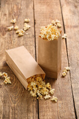 Paper bags with tasty popcorn on wooden background