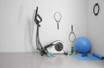 Different sports equipment with fitness ball near brick wall