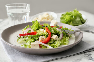 Plate with fresh Greek salad on light background