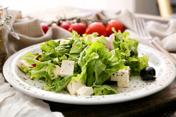 Plate with fresh Greek salad on wooden board, closeup