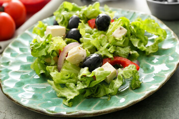 Plate with fresh Greek salad on grunge background, closeup