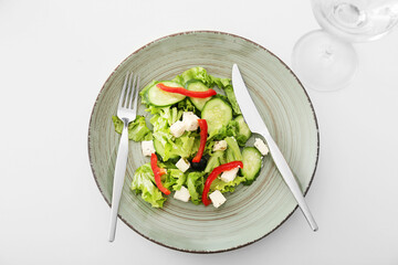 Plate with fresh Greek salad and glass of beverage on light background