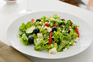 Plate with fresh Greek salad on table in restaurant